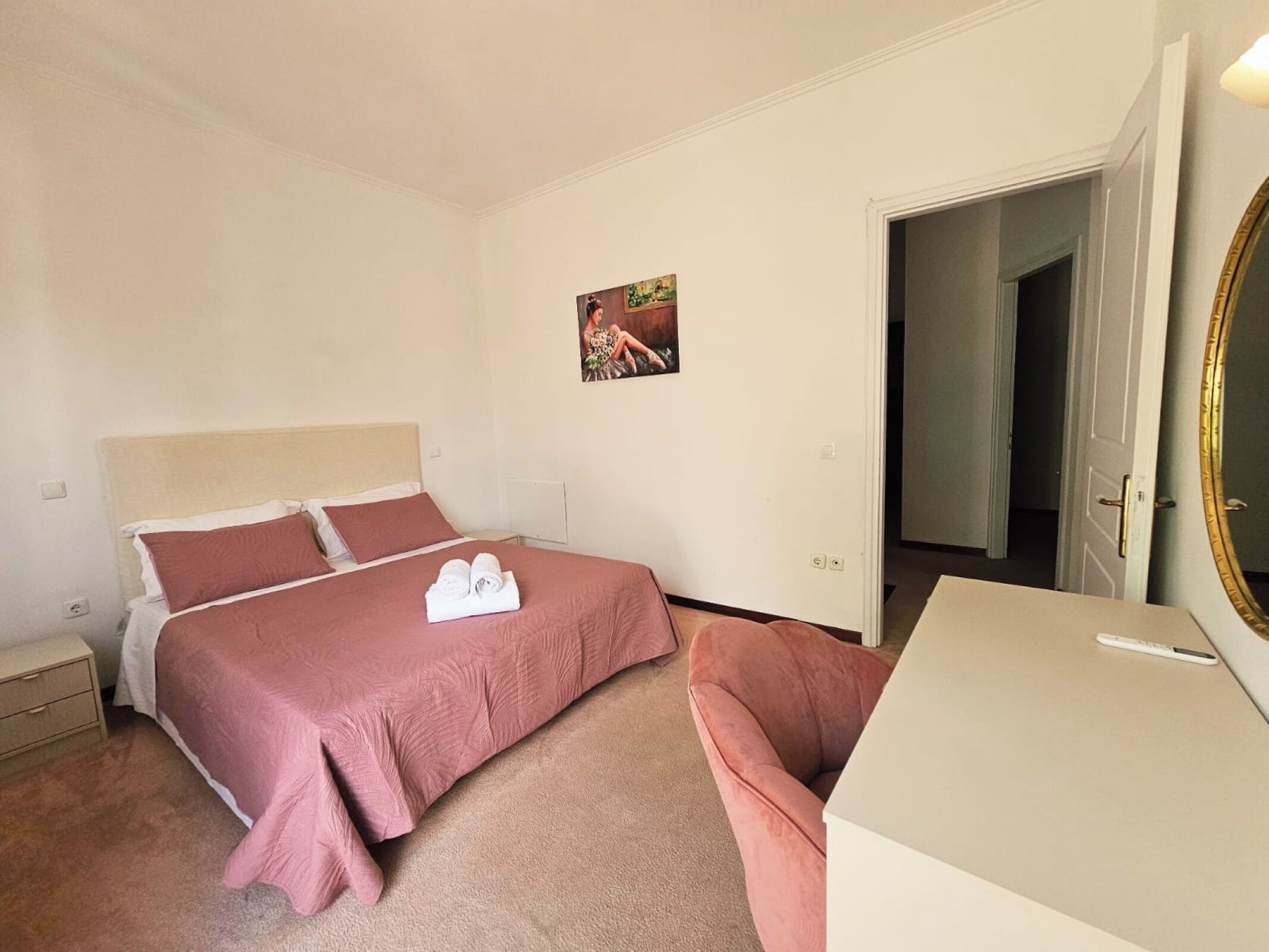 A bedroom with a bed, a bedside table, a chair, a desk, and a mirror.