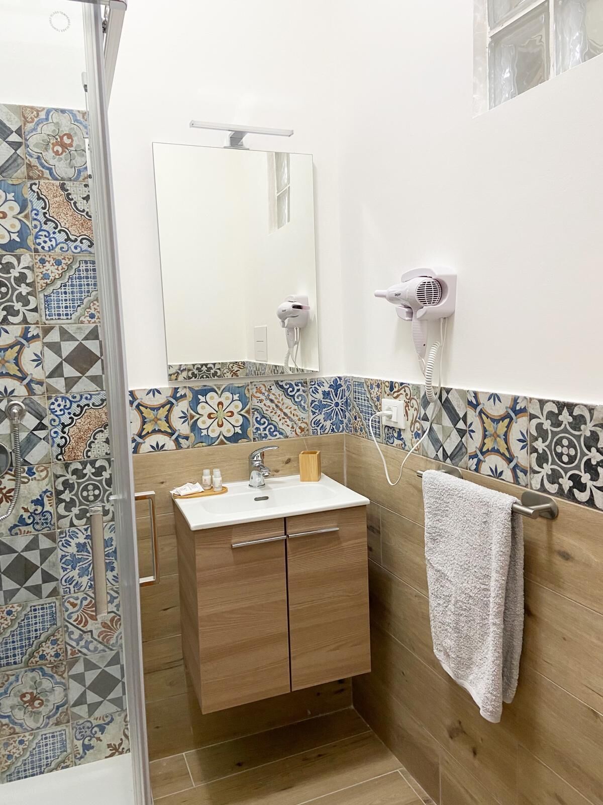 Une salle de bain équipée d’une douche, d’un lavabo, d’un miroir et d’un porte-serviettes.