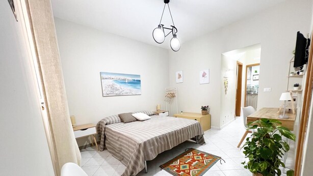 A bedroom with a bed, bedside table, chair, and a desk with a lamp. - Angela's House (Monreale)