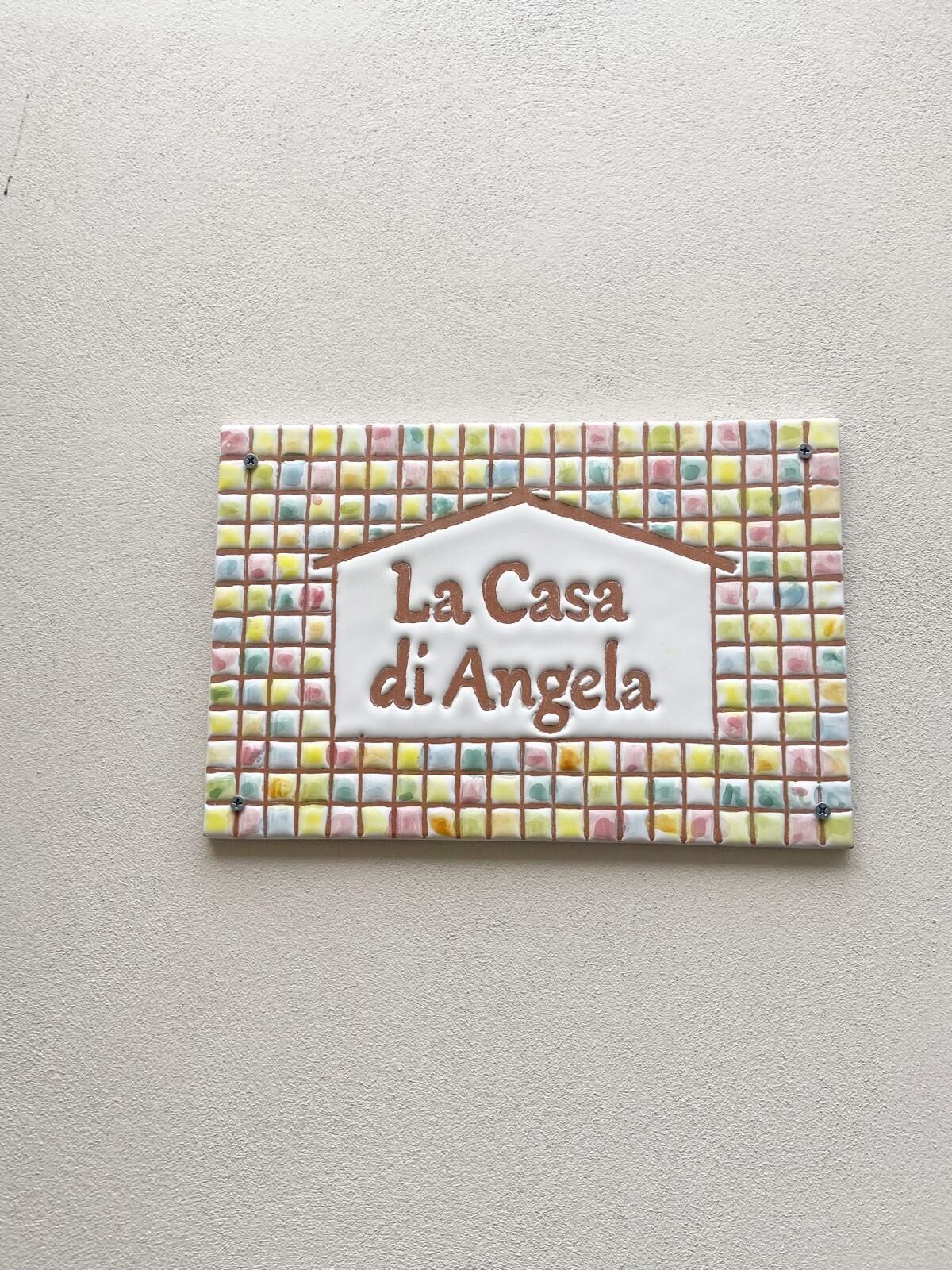 Een bord met de tekst 'La Casa di Angela' op een betegelde achtergrond.