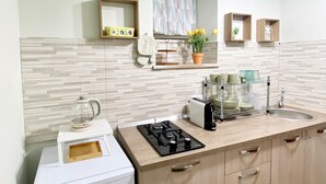 A compact kitchen with a built-in refrigerator, a gas stove, a sink, and a countertop with a dish rack. - Angela's House (Monreale)