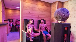 A sauna room with wooden walls and a digital thermometer displaying 20 degrees Celsius.