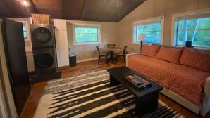 A cozy loft-style room with a large bed, a dining area, and a kitchen with a washer and dryer.