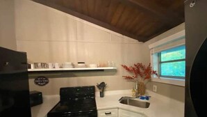A kitchen with white cabinets, a black stove, and a window with a view.