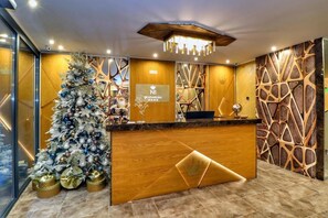 A reception area with a Christmas tree, a wooden reception desk, and a decorative wall with geometric patterns.