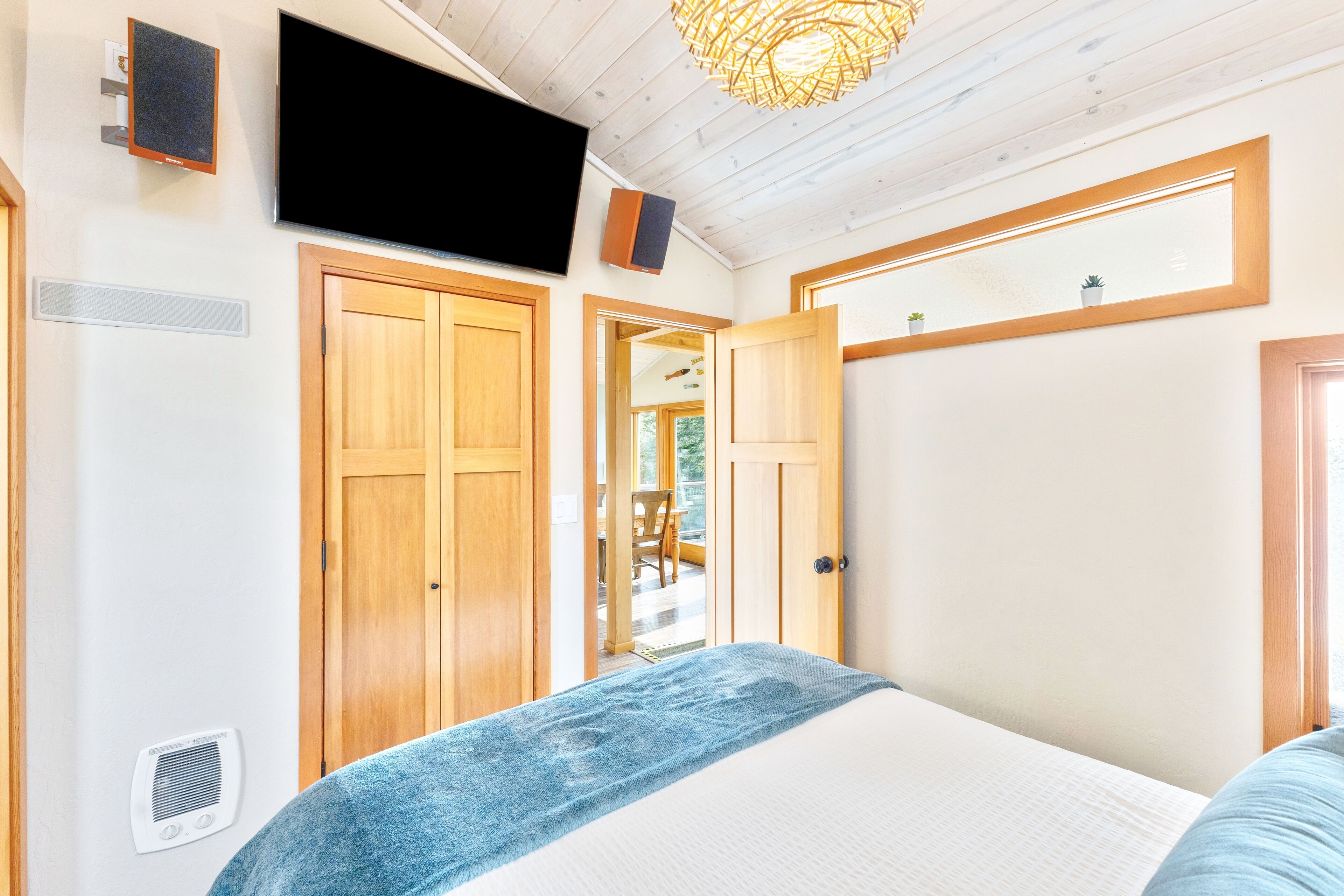 A bedroom with a bed, wooden wardrobe, a television, and a ceiling light fixture.