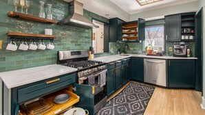 A modern kitchen with green cabinets, a stainless steel stove, and a large window. - Spacious Family Retreat: King Beds+Arcade+Playground. Minutes from Zoo/Downtown (Omaha)