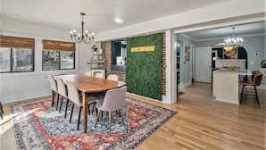A modern kitchen with a green wall, wooden cabinets, and a central island. - Spacious Family Retreat: King Beds+Arcade+Playground. Minutes from Zoo/Downtown (Omaha)