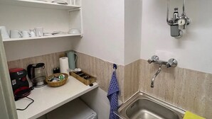 Et kompakt køkken med vask, kaffemaskine og lille køleskab.