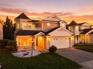 A two-story residential house with a garage, a covered porch, and a well-maintained lawn.