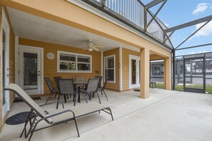 A covered patio with a table and chairs, a ceiling fan, and a view of the street.