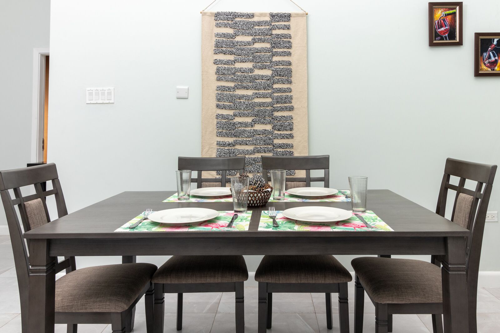 A dining area with a rectangular table set for four, surrounded by four chairs.