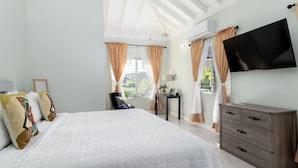Un dormitorio moderno con una cama grande, un televisor en la pared y un escritorio con lámpara.