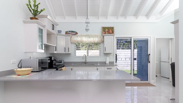 Una cocina moderna con armarios blancos, una isla grande y vistas al exterior.