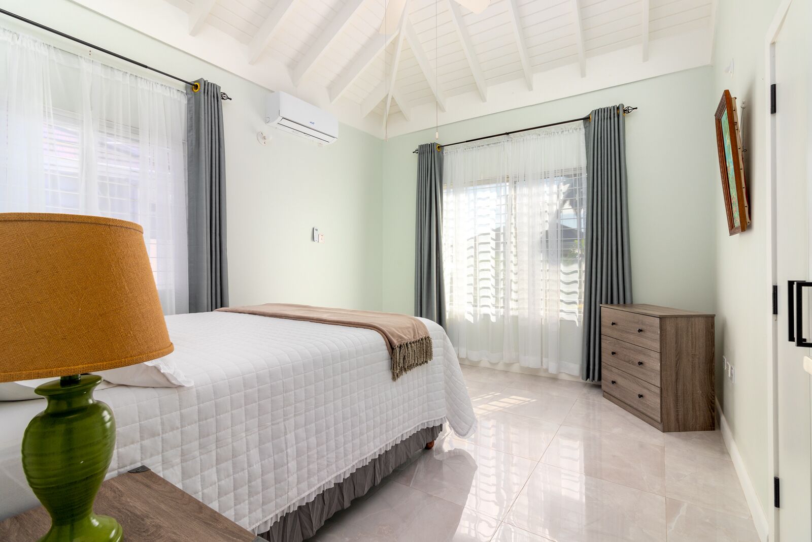 Ein Schlafzimmer mit einem Bett, einem Schminktisch, einer Klimaanlage und einer Lampe.