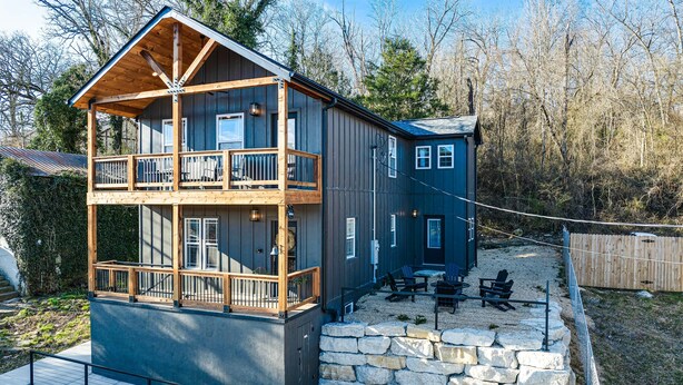 A two-story cabin with a balcony, stone steps, and outdoor seating. - Historic Hollister Home: Shop, Dine & Drink Nearby (Hollister)