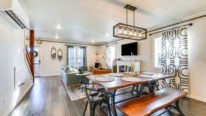 A dining area with a wooden table, benches, and a chandelier. There is a staircase leading to another room, and a television mounted on the wall. - Historic Hollister Home: Shop, Dine & Drink Nearby (Hollister)