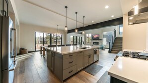 Uma cozinha moderna com uma ilha grande, eletrodomésticos embutidos e vista para o exterior.