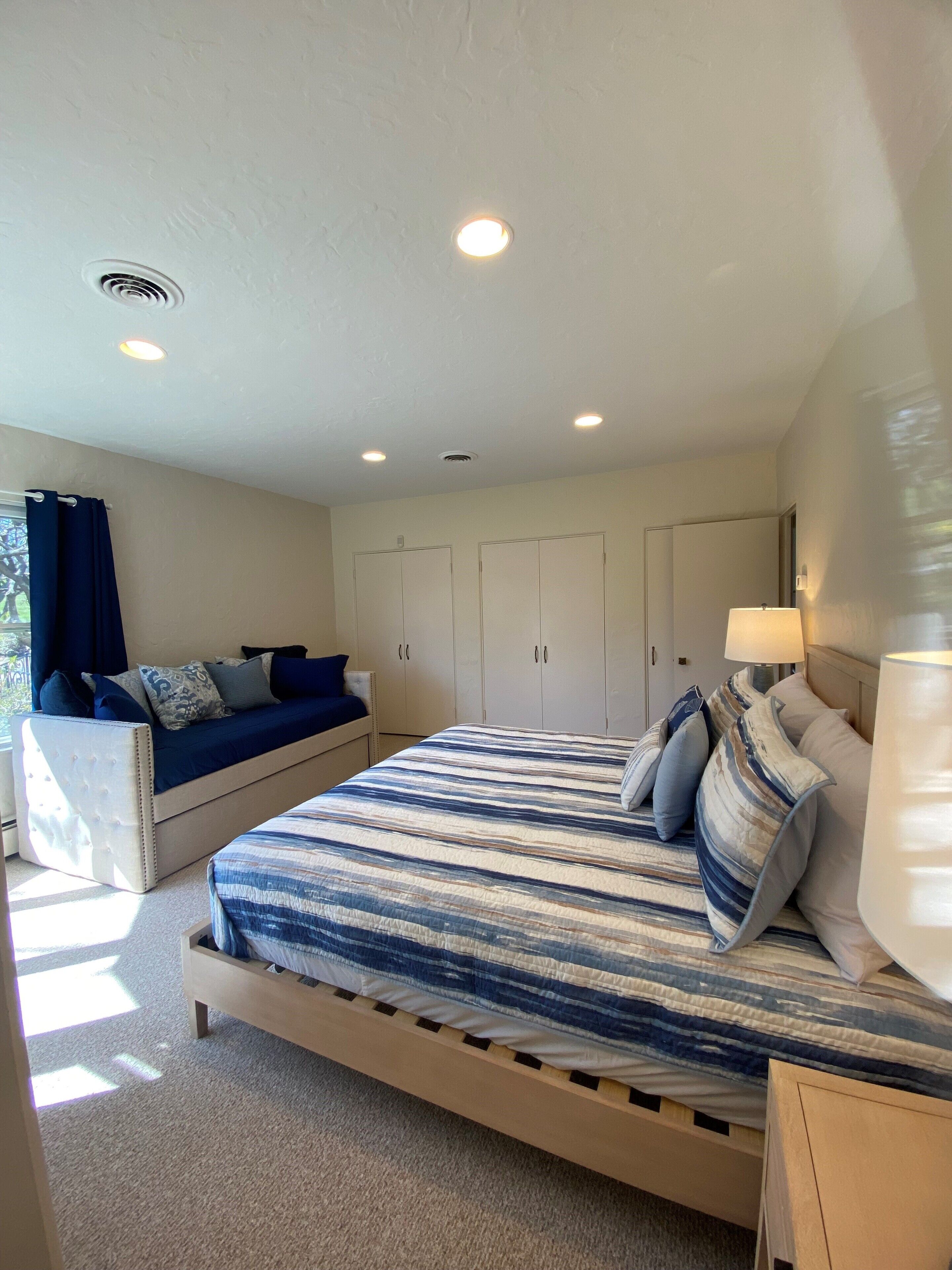 Un dormitorio con cama, sofá, armario y lámpara.