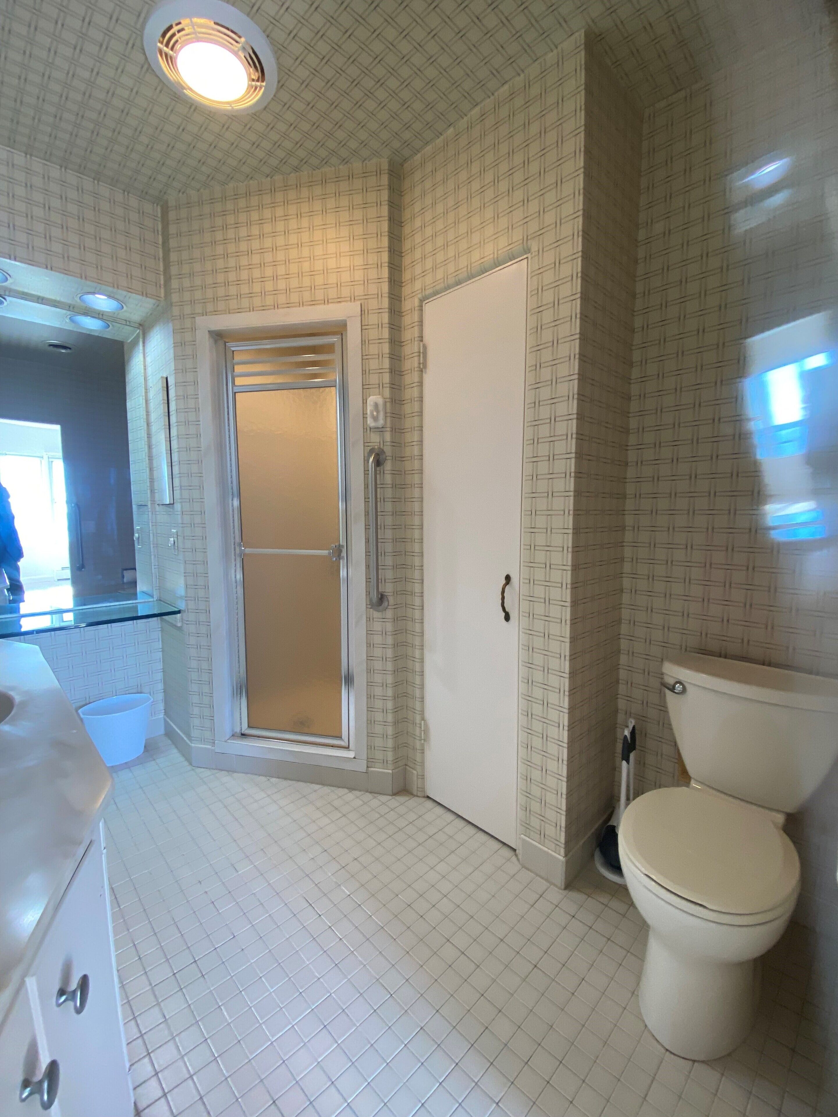 Un baño con inodoro, ducha con puerta de vidrio, lavamanos y espejo.