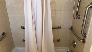 A bathroom with a bathtub, grab bars, and a shower curtain. - Dav-Ed Motel (Kingsville)