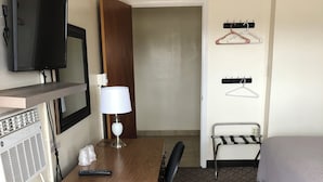 A hotel room with a wooden desk, a television, a lamp, a bed, and a coat rack. - Dav-Ed Motel (Kingsville)