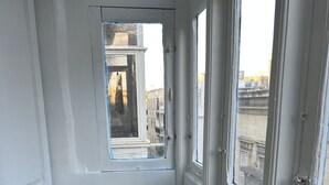 Une pièce avec une table en bois, des murs blancs et une fenêtre donnant sur des immeubles.