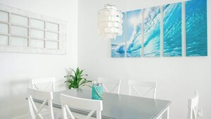 Un espace repas comprenant une table, des chaises, une plante et un tableau accroché au mur.