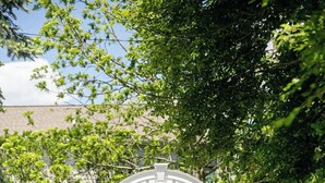 Une structure arquée blanche se dresse dans un espace aménagé, avec un chemin pavé qui y mène.