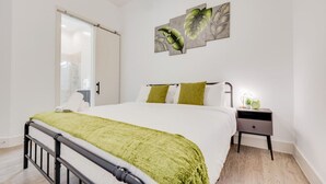 Un dormitorio con una cama, una mesita de noche, una obra de arte en la pared y una puerta corredera.