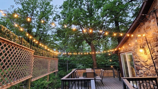 Una terrazza esterna con un recinto in legno a graticcio, luci a tenda e un edificio in pietra.
