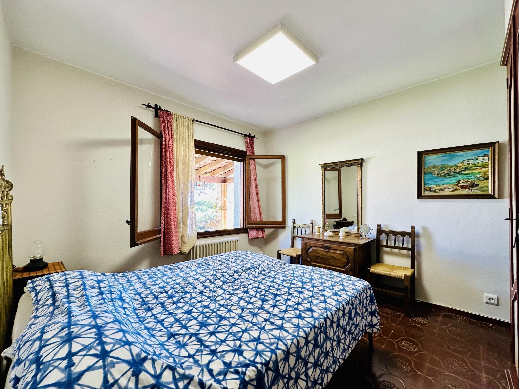 A bedroom with a bed, dresser, mirror, and a painting on the wall.