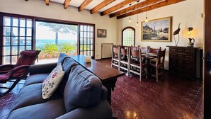 A cozy room with a wooden ceiling, a dining area, and a view of the sea. - Maset CostaBravaSi - with pool, views, parking (Sant Feliu de Guíxols)