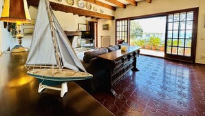 A spacious living area with a sailboat model, a fireplace, and a large window offering a view of the outdoors. - Maset CostaBravaSi - with pool, views, parking (Sant Feliu de Guíxols)