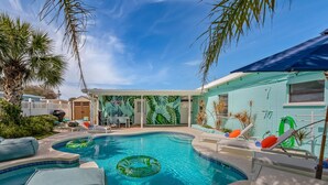 A swimming pool with lounge chairs and a tropical mural.