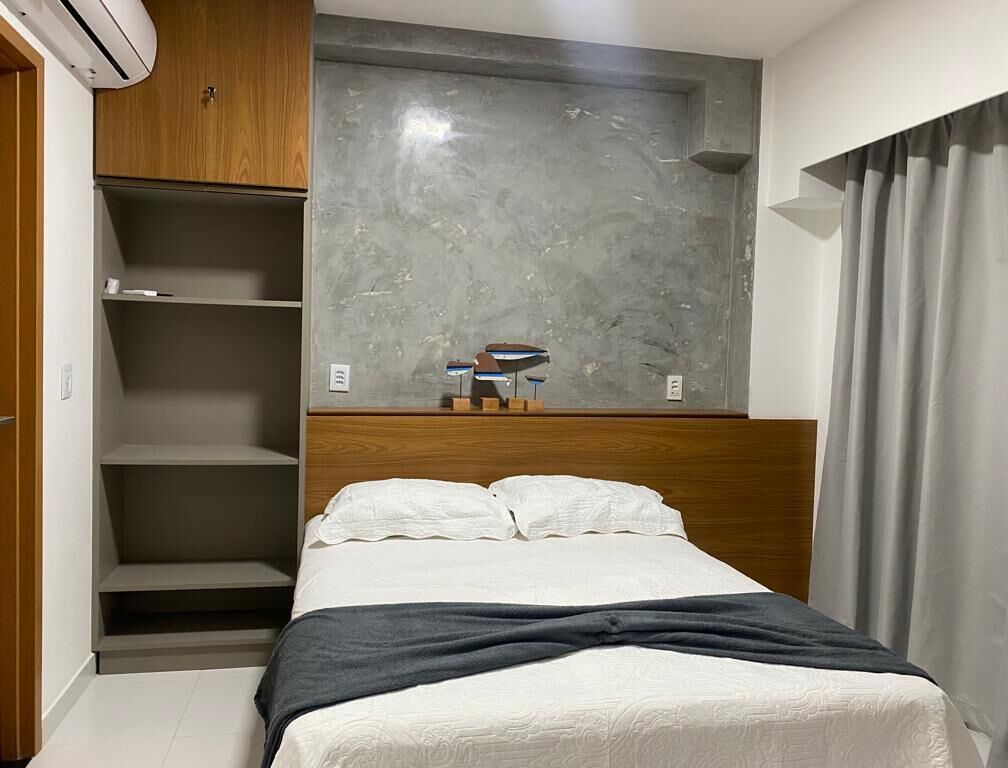 Ein Schlafzimmer mit einem Bett, einem Holzschrank, einer grauen Marmorwand und einem grauen Vorhang.
