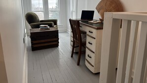 A room with a desk, chair, and a small ottoman with books. - Charming rustic retreat with Bay of Fundy Views, escape to our serene haven. (Hampton)