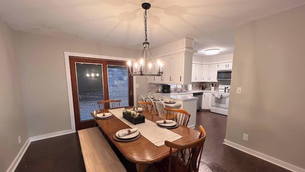 Un comedor con una mesa de madera, sillas y un banco. Se ve el exterior a través de la puerta.
