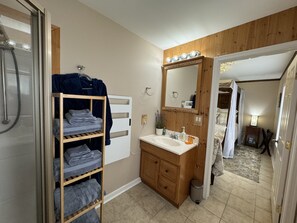 A bathroom with a wooden vanity, a sink, a mirror with lights, a towel rack, and a shower area. - Romantic or Family Vacay w/ Stunning Mtn Views & Hot Tub near Crabtree Falls (Montebello)
