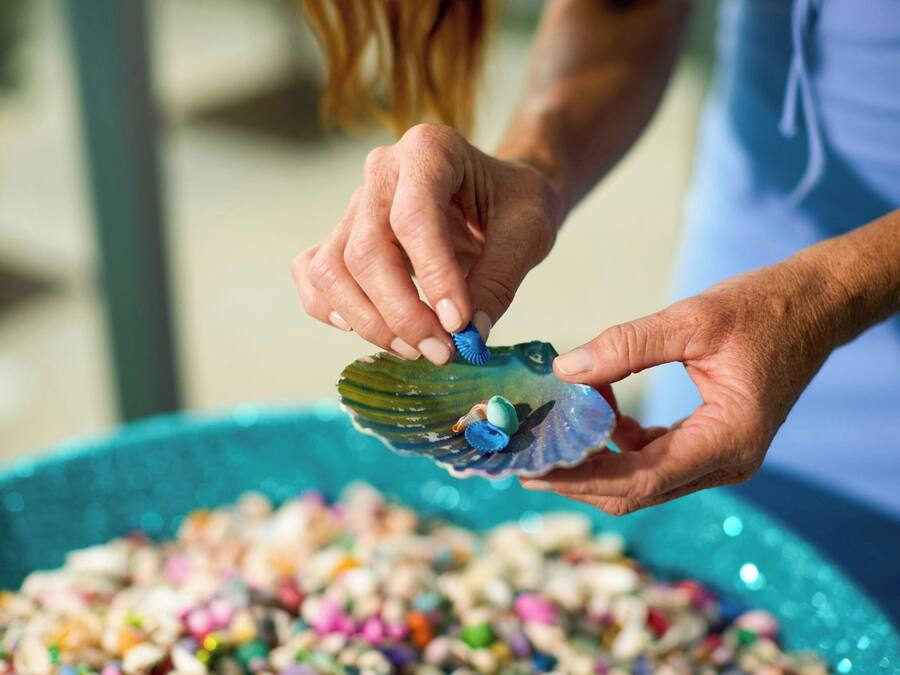 Una persona sosteniendo una concha con objetos de colores en su interior.