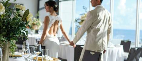 Una mesa de recepción de boda con manteles blancos, platos dorados y blancos, y cristalería transparente.