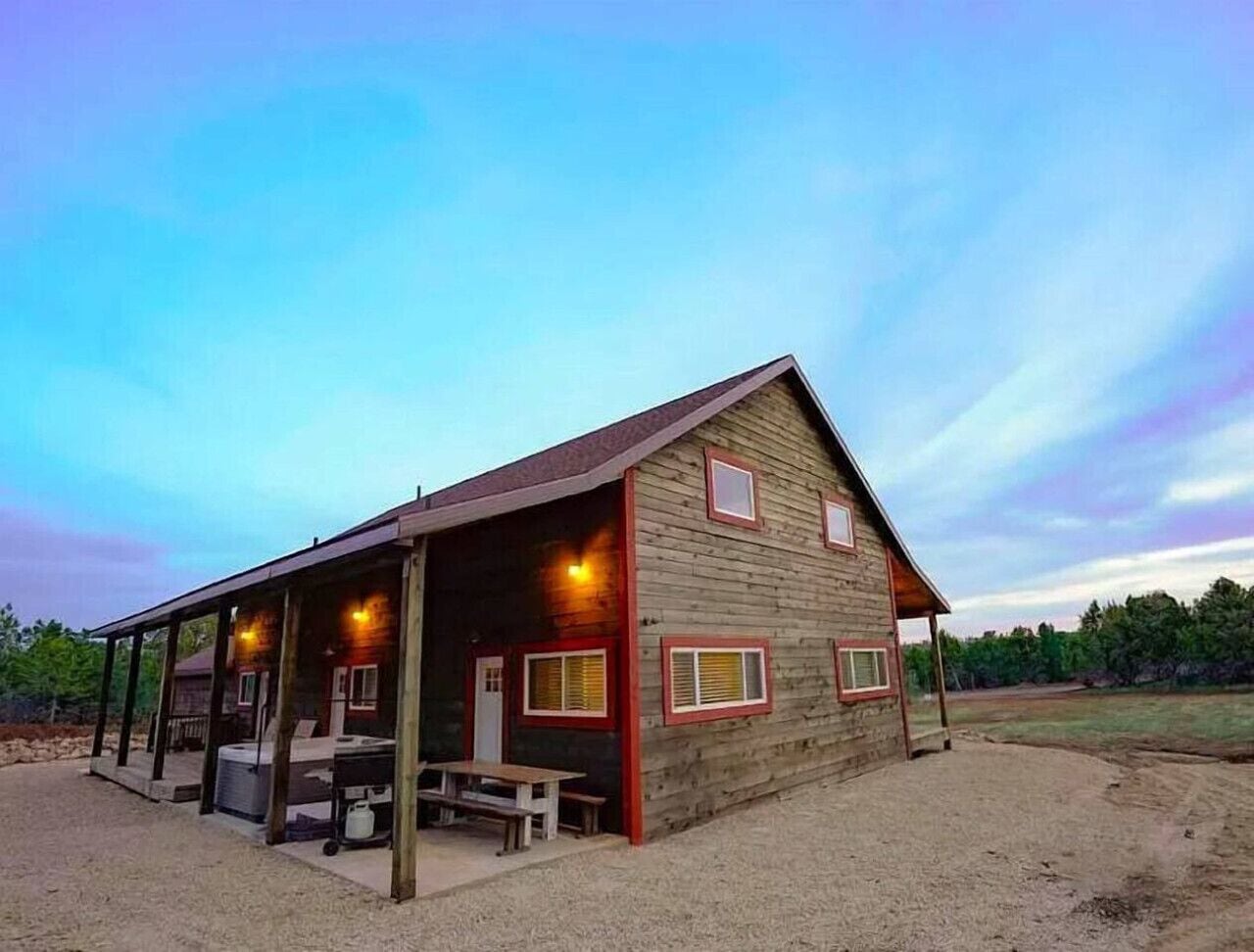 A rustic cabin with a covered porch, a small table, and a bench.