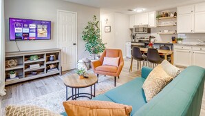A living room with a TV mounted on the wall, a sofa, a coffee table, and a bookshelf.
