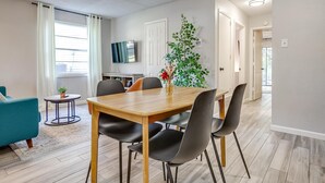 A modern dining area with a wooden table and black chairs, a small side table with a plant, and a teal sofa.
