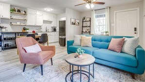 A modern living room with a teal sofa, a pink armchair, and a coffee table.