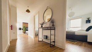 Una sala de estar moderna con suelo de madera, un sofá, una mesita de centro y un espejo grande.