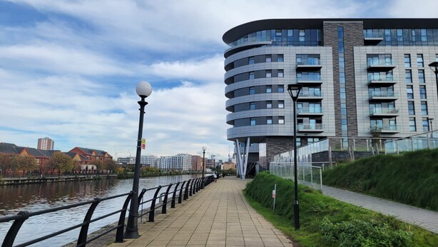 Un edificio moderno con fachada curva, un paseo marítimo y cielo despejado.