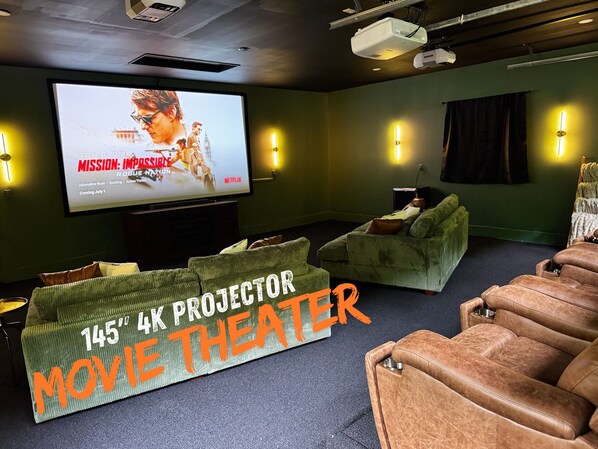 Sala cinema con proiettore 4K da 145 pollici, pareti verdi e poltrone in pelle reclinabili.