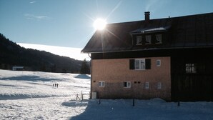 Paisaje nevado con un edificio de madera que tiene fachada de ladrillo y varias ventanas.