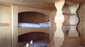 Habitación con literas de madera y estructura de estanterías empotradas.